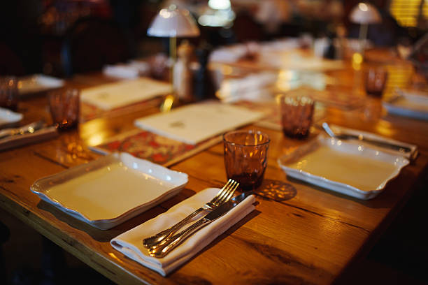 A warm and inviting table is prepared for dinner with empty plates, cutlery, and soft lighting creating a relaxed atmosphere for guests.