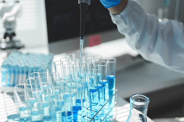 istock Close-up of a scientist's gloved hand holding a micropipette, dropping blue liquid into a test tube in a modern laboratory filled with equipment and test tubes 2252144236
