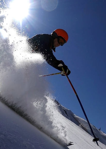 Male skier riding in the deep snow with snowcovered mountainrange in the background on a sunny day in the skiresort of St. Anton am Arlberg in Tirol, Austria. Ski Arlberg is one of the biggest skiresorts in Europe and the biggest in Austria. Since the winter of 2013–14, the villages of St. Anton, Stuben, St. Christoph, Lech, Oberlech, Zürs and Zug have been linked to the Warth-Schröcken ski area which makes Ski Arlberg the largest connected ski area in Austria