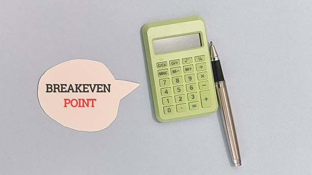 istock Breakeven point concept displayed next to a light green calculator and a silver pen on a light blue surface. 2252146374