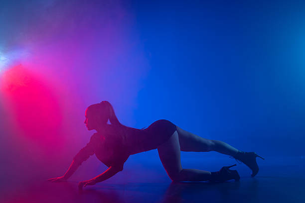 Silhouette of woman practicing heels floorwork in blue pink neon smoke, wide copy space for dance promotion