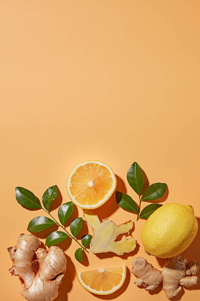 istock Minimal flat lay showing lemons, ginger roots, and leaves placed on a orange surface. Background of ingredients used in detox drinks, cough relief tea, and clean eating, copy space 2252150746