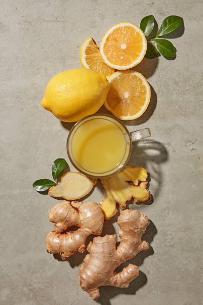 Fresh lemon, ginger roots and slices arranged on cement background. The composition feels balanced and suitable for detox and immunity themes. Top view