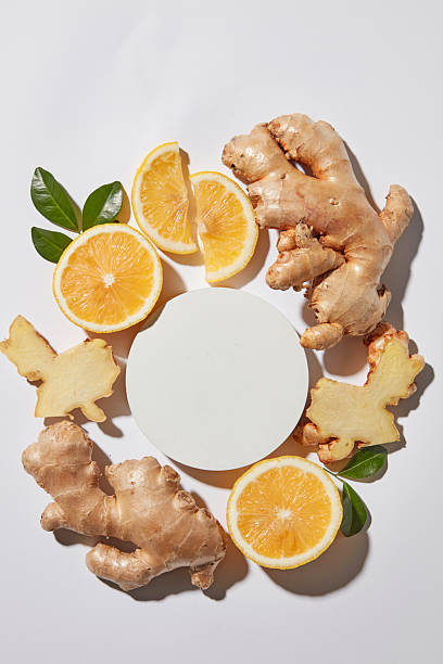 Flat lay featuring an empty round plate framed by lemon and ginger on light background. Space for product placement, herbal ingredients and natural health themes