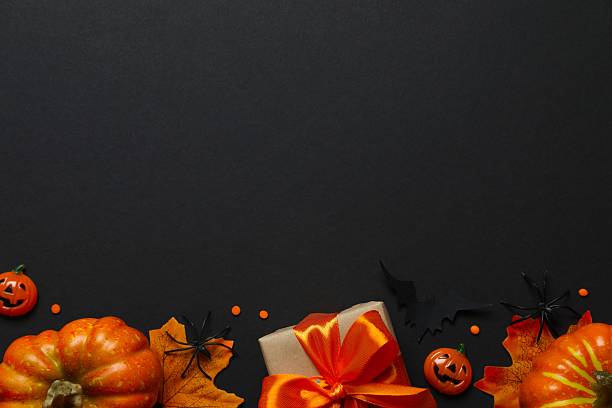 istock Happy Halloween concept. Festive background design featuring gift box, pumpkins, spiders and confetti. 2252154353