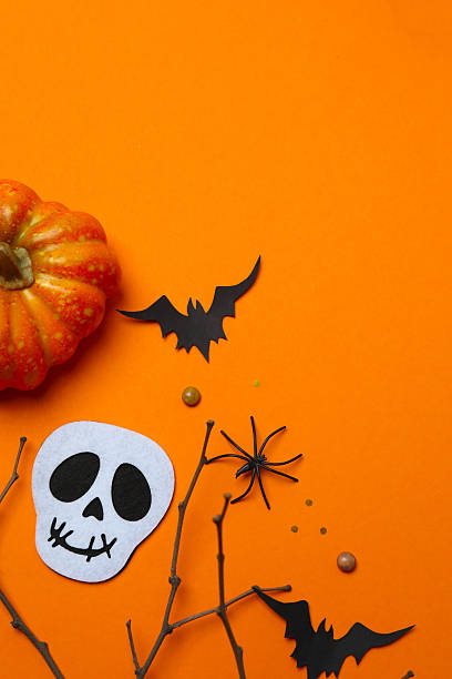 istock Halloween composition with black paper bats, skull, pumpkins and branches on orange background, top view, space for text 2252156399