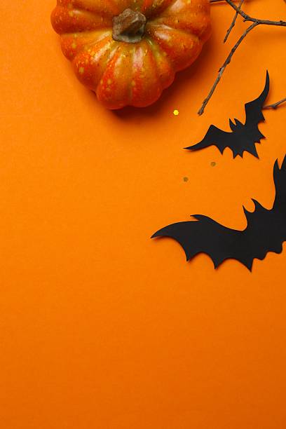 istock Halloween composition with black paper bats, pumpkin and branches on orange background, top view, space for text 2252156402