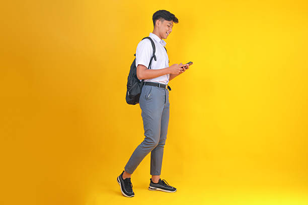 istock Trendy Young Student Using Smartphone on Bright Yellow Background 2252158056