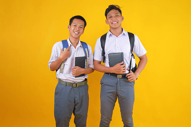 Cheerful Students Ready for School With Backpacks and Notebooks on Vibrant Yellow Background