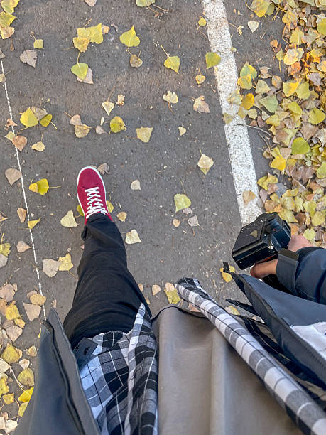 istock A person strolls a leaf-covered path on a sunny autumn day, camera in hand 2252159558