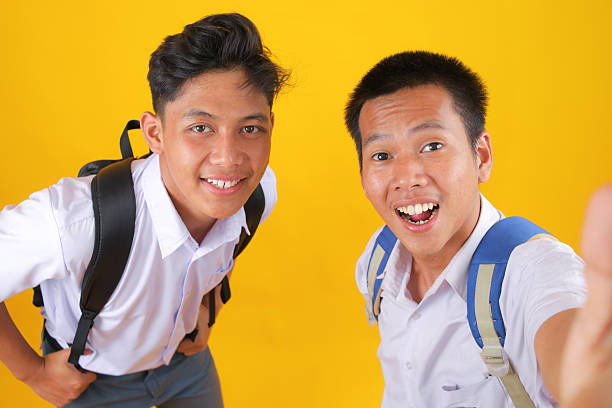 Excited Students Taking Selfie Together on Bright Yellow Backdrop