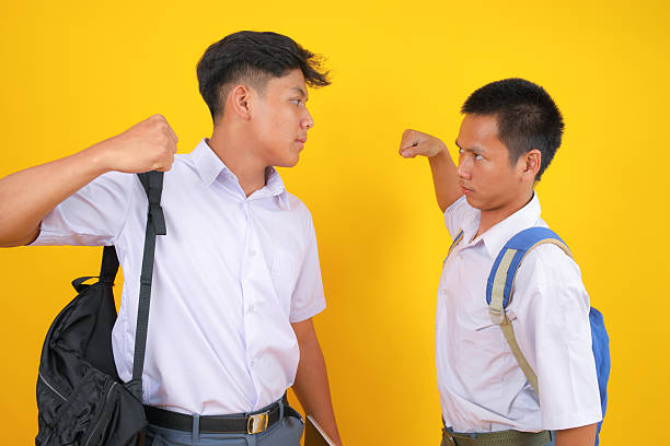 Tension Rises Rival Students Face Off Ready for Confrontation in Youthful Dispute With Bright Yellow Backdrop