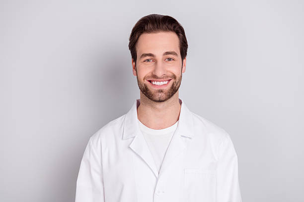 istock Photo of positive thoughtful young doc man dressed white coat smiling looking empty space isolated grey color background 2252161639