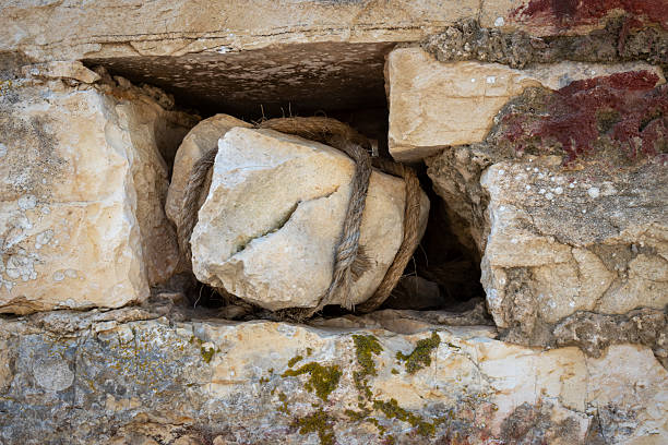 Hole in a stone wall with a gap for one stone, which is roped. Abandoned house in the countryside. Paxos, Greece.