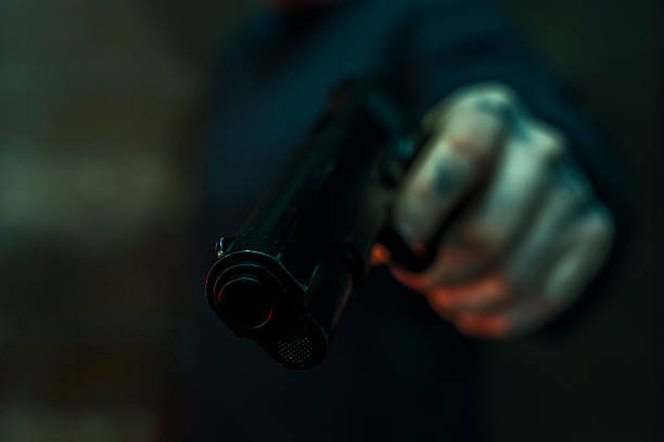 istock Tattooed hand holding handgun in dark setting 2252170293
