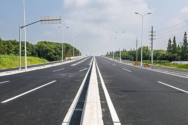 istock Empty newly paved asphalt road stretching into the distance under a clear sky. 2252172108