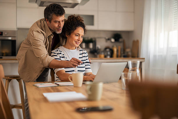istock Couple Working Together at Kitchen Table On Laptop, Pointing At Screen, Cozy Home Scene 2252175526
