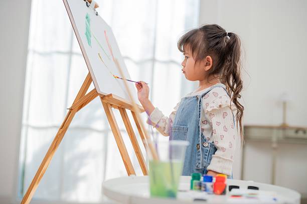 istock Child paints on canvas while standing at easel in bright room with natural light during afternoon 2252179642