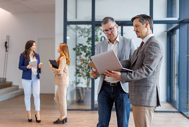 istock Business colleagues collaborating on laptop in modern office hallway 2252181225
