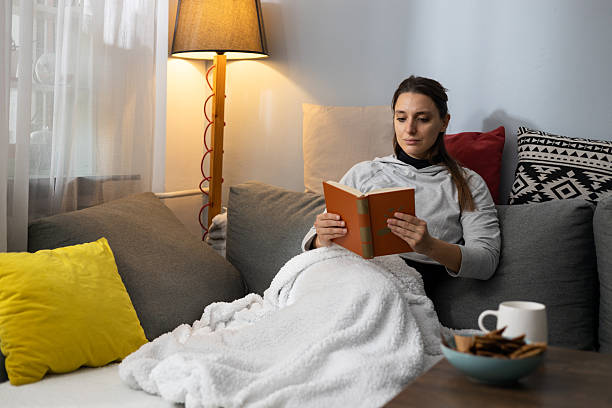 istock Woman relaxing reading book on cozy home couch 2252181821