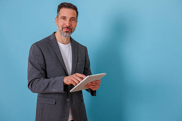 istock Man working on digital tablet, smiling against blue background, representing modern professional technology 2252182609