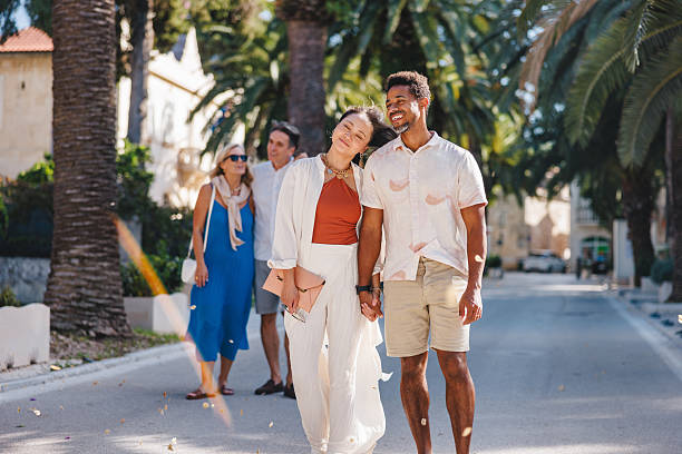 istock Content Couples Walking on Palm Lined Dalmatian Street in Sunlight 2252184165