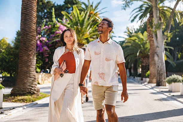 istock Happy Couple Walking on Sunlit Path Lined with Palms 2252184359