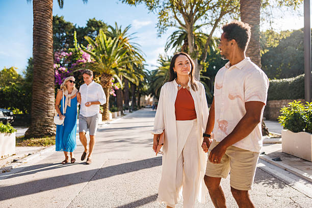 istock Happy Couples Walking on Sunlit Path with Palm Trees 2252184396