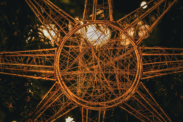Close-up photograph of an illuminated wire star Christmas decoration glowing with warm festive lights. A cozy seasonal image ideal for holiday backgrounds, festive design projects, and winter celebration concepts.