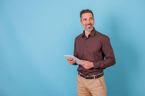 istock Smiling businessman holding a digital tablet, looking away in a professional setting with copy space 2252186952