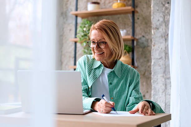 istock Mature adult woman smiling using laptop writing notes 2252187030