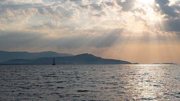istock Sailboat on Calm Sea with Sun Rays and Mountains at Sunset 2252189928