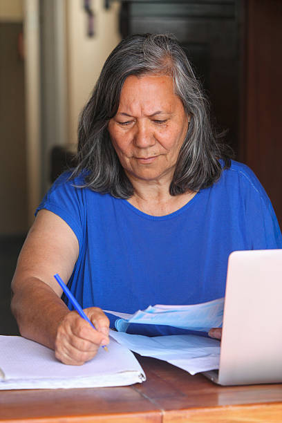 istock Senior woman using laptop and reading documents at home 2252190252