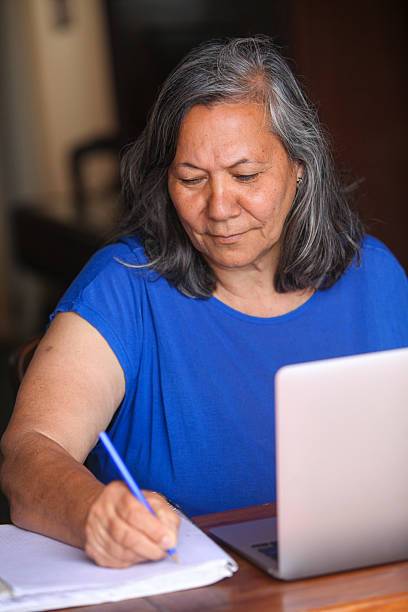 istock Senior woman using laptop and reading documents at home 2252192861