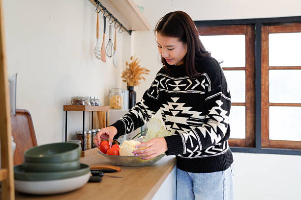 istock young woman showing tomato standing in kitchen 2252193249
