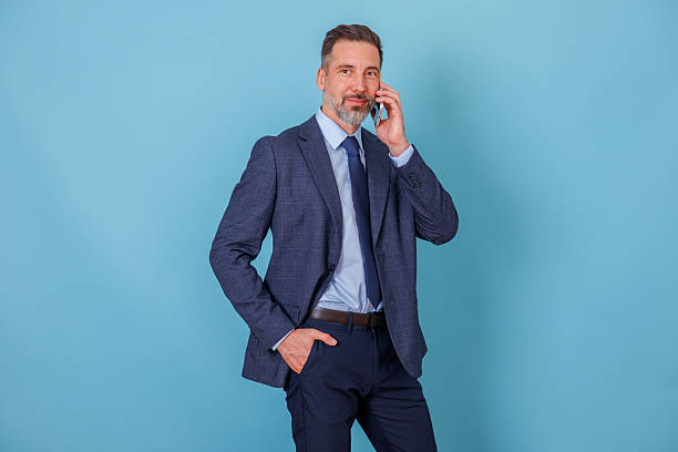 istock Businessman making phone call, communicating on smartphone, standing with hand in pocket, looking confident 2252193398