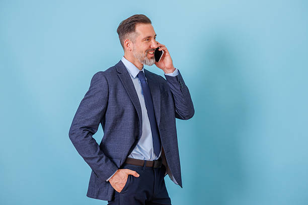 istock Businessman talking on mobile phone against a blue background, communicating and networking 2252193951