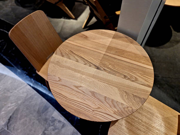 istock table is round and made of solid oak wood. It is made of natural oak, known for its durability and distinctive wood grain. This material is often available as dining or coffee tables in various shape 2252194792
