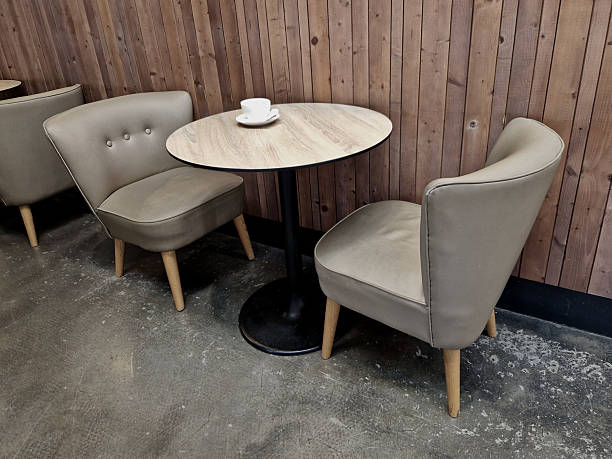 istock is a cafe seating area with two upholstered chairs and an oval table. gray-brown upholstery. table has a wooden top and a black cast iron. There is a small white coffee cup on the table. wooden 2252194796
