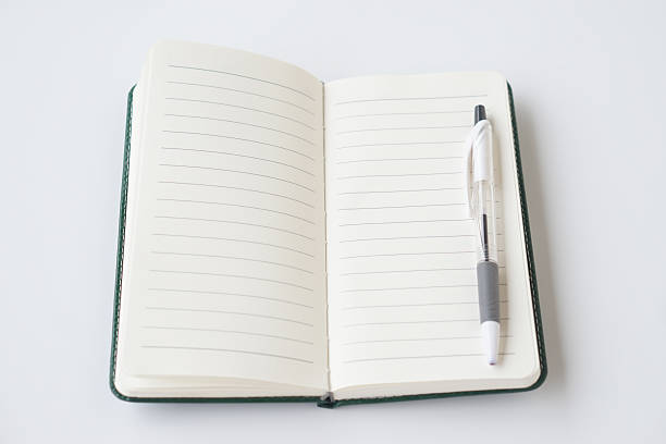 istock Open blank notebook with lined pages and pen placed on top, isolated on white background. Minimal workspace concept for writing, planning, education, diary, notes, business, and creative ideas. 2252195224