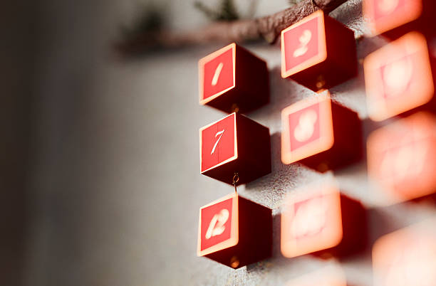 Close-up of red square cubes displaying white numbers on a wall. Warm glow and soft focus create a cozy holiday mood, perfect for Christmas campaigns and festive countdown themes.