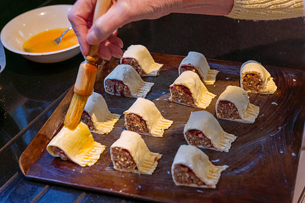 Sausage rolls made with turkey being brushed with milk and egg before being placed into the oven for baking