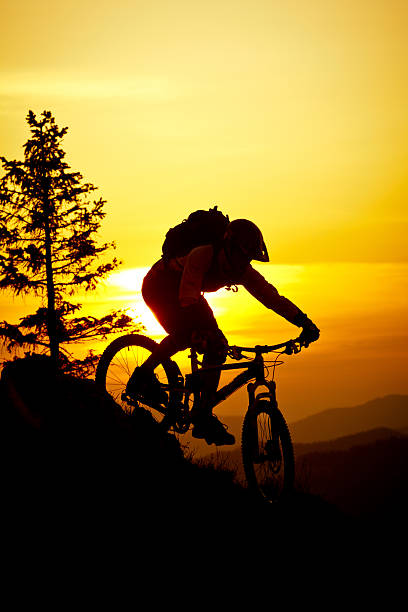 Mountain biker riding bike on a mountain trail along the edge of a ridge.
