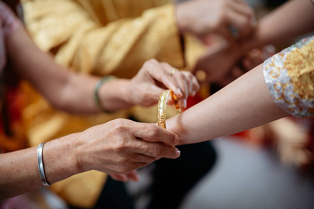 Gold jewelry is placed on the bride’s wrist by parents as part of a traditional Chinese wedding ceremony. The photo conveys cultural heritage, symbolic blessings, and intergenerational participation in wedding customs.