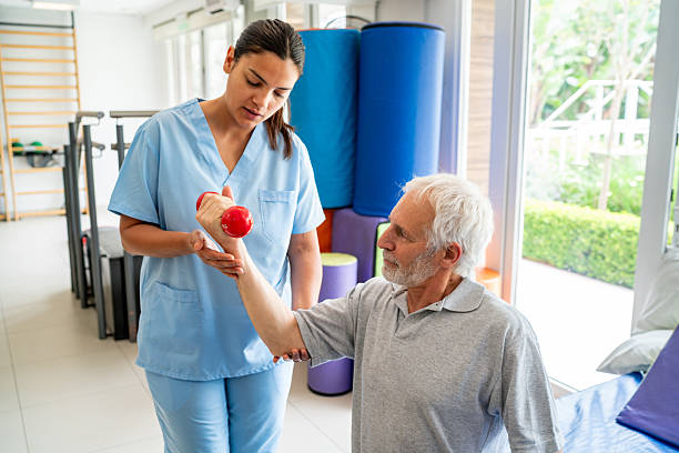 istock Physical therapist helping a senior man doing exercises with dumbbells 2252206166