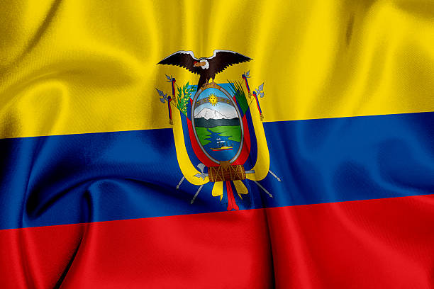 The image shows the national flag of Ecuador, featuring three horizontal stripes in yellow, blue, and red. At the center is the country’s coat of arms, displaying the Andean condor, Mount Chimborazo, the Guayas River, and symbolic elements representing prosperity, independence, and national strength.