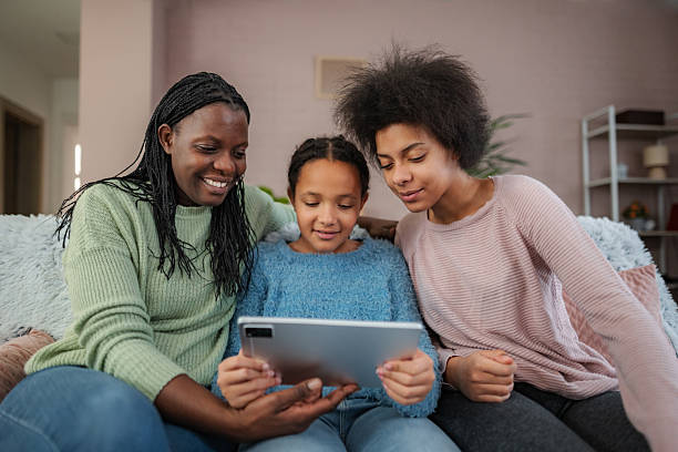 istock Mother and daughters enjoying digital tablet at home 2252208333
