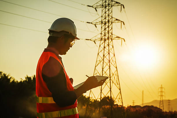 istock High Voltage Tower and Power Lines with Engineer Silhouette at Golden Hour 2252210823