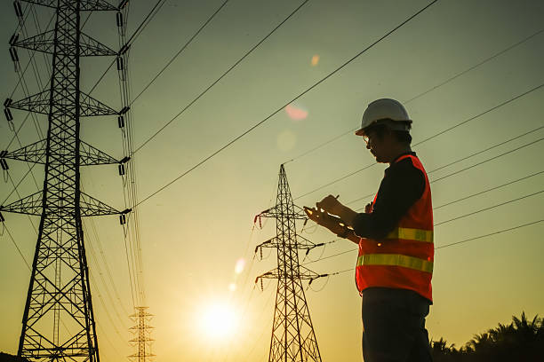 istock High Voltage Tower and Power Lines with Engineer Silhouette at Golden Hour 2252210833