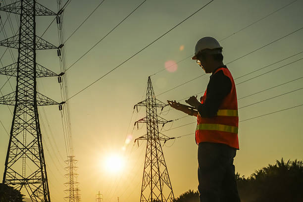 istock High Voltage Tower and Power Lines with Engineer Silhouette at Golden Hour 2252210834